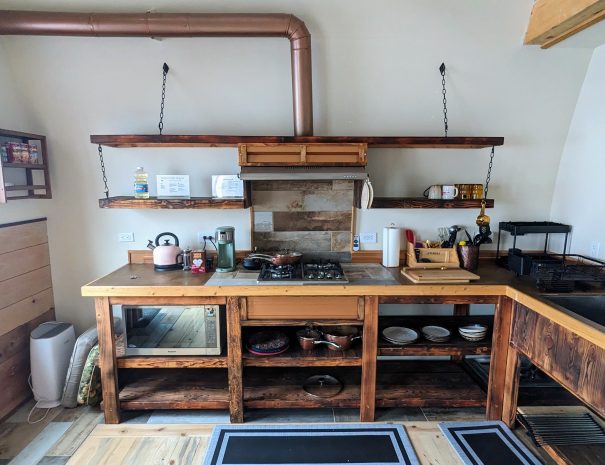 FULL KITCHEN: Summon your inner chef in the functional bunkhouse kitchen with a four-burner propane cooktop, microwave, pots and pans, and cutlery and utensils.