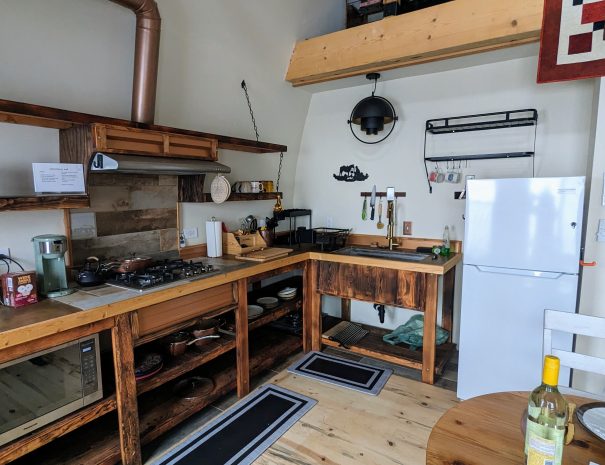 FULL KITCHEN: Your kitchen features a farmhouse sink, cutting board, microwave, propane burners, utensils, mugs, plates, cutlery and fridge/freezer.