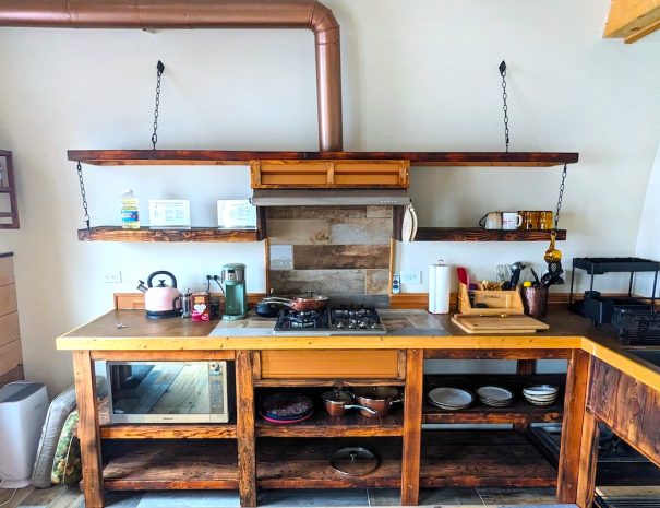 FULL KITCHEN: Summon your inner chef in the functional bunkhouse kitchen with a four-burner propane cooktop, microwave, pots and pans, and cutlery and utensils.